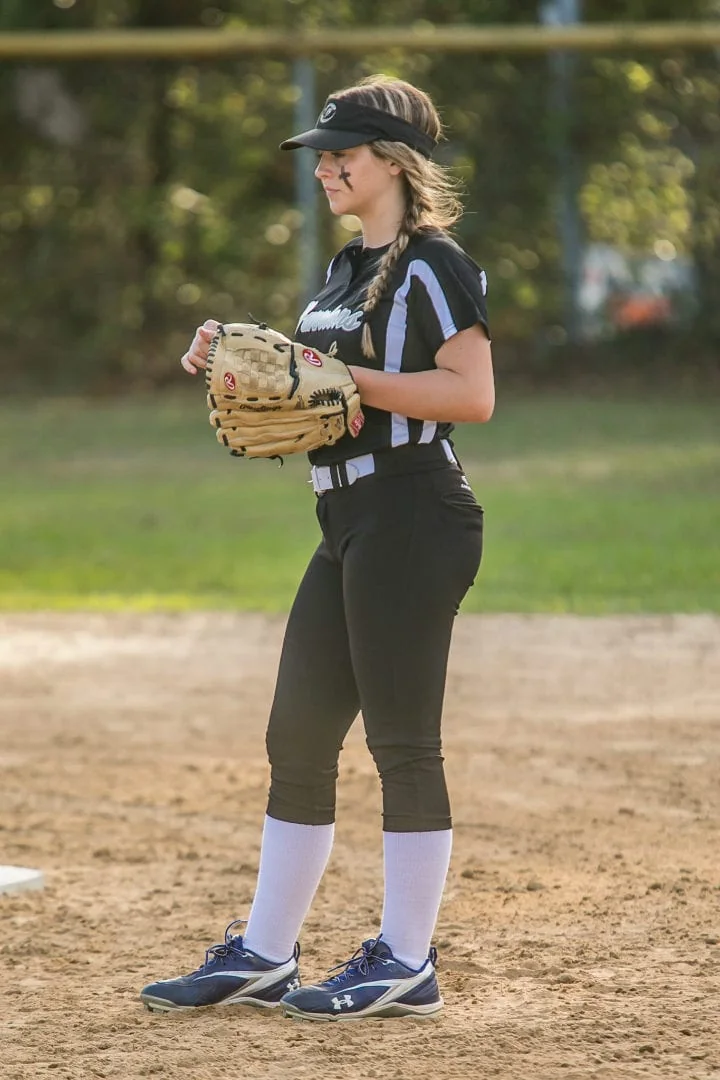 Girl standing with her catching mitt.