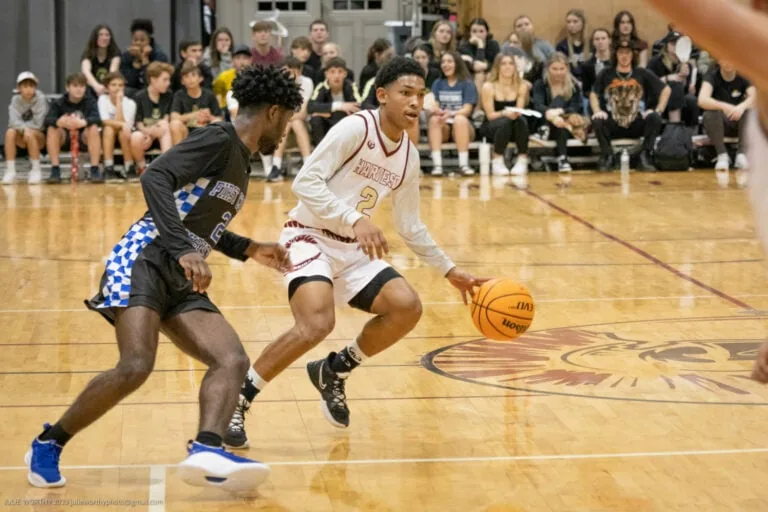 An HCS student dribbling a basketball and being guarded by the other team.