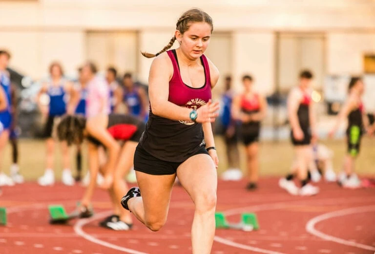 Track girl running around a track.